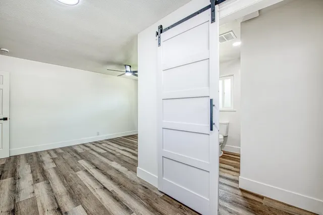 an empty room with wooden floor fan and windows