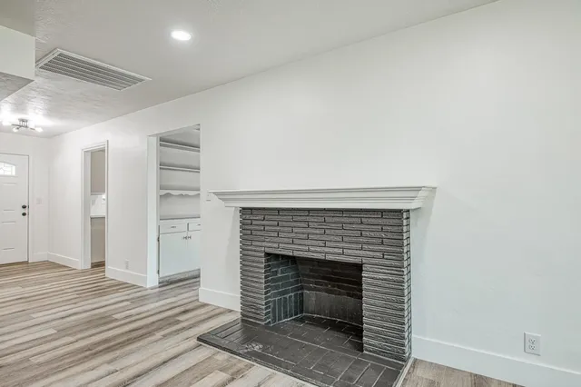 an empty room with wooden floor windows and fireplace