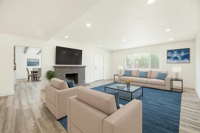a large white kitchen with a white countertops a dining table and chairs with wooden floor