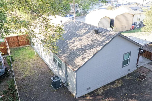 a backyard of a house with large trees and lawn chairs