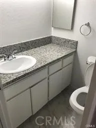 a bathroom with a granite countertop sink and a toilet
