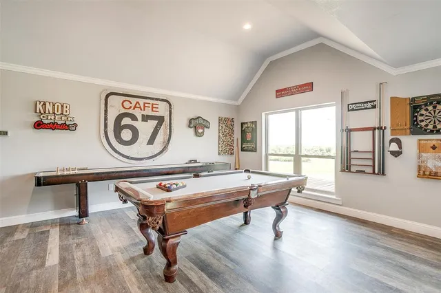 a living room with a pool table and windows