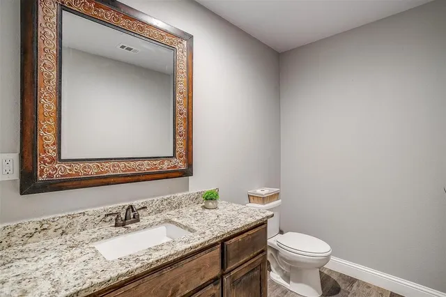 a bathroom with a granite countertop sink toilet and mirror