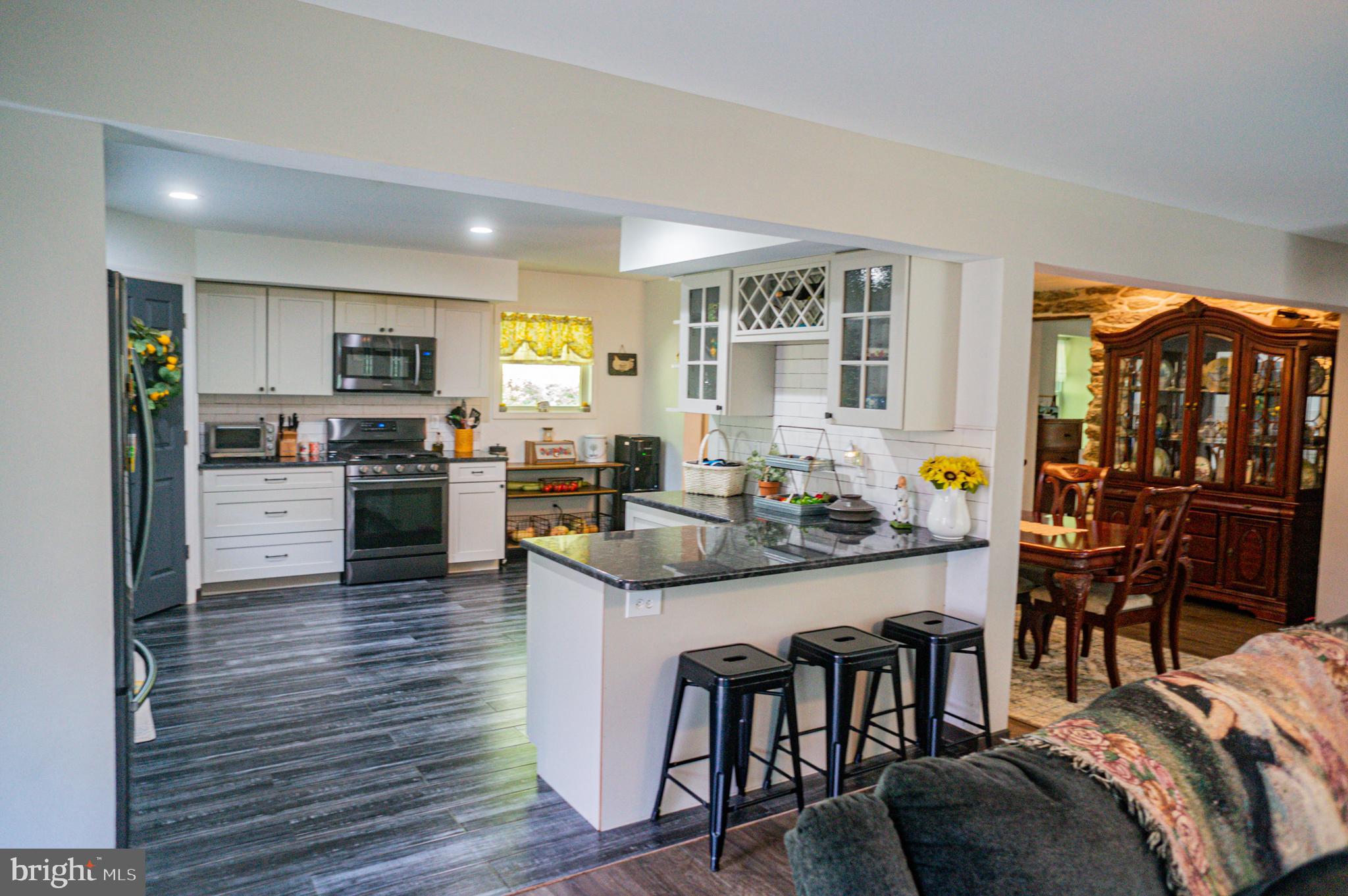 988 Kratz Road Glen Rock, PA 17327 - Photo 41 of 97 a kitchen with stainless steel appliances granite countertop a stove top oven a sink dishwasher a dining table and chairs with wooden floor
