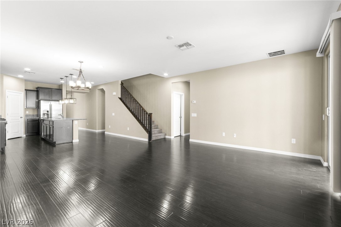 11048 Prairie Grove Road Las Vegas, NV 89179 - Photo 12 of 75 Rich hardwood floors unite an open-concept living space and a modern kitchen, creating seamless flow.