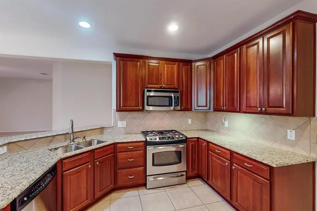 a kitchen with granite countertop stainless steel appliances a stove sink and cabinets