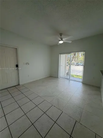 an empty room with windows and ceiling fan