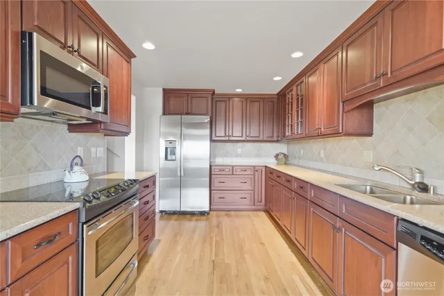 a kitchen with stainless steel appliances granite countertop a sink a stove cabinets and a dining table