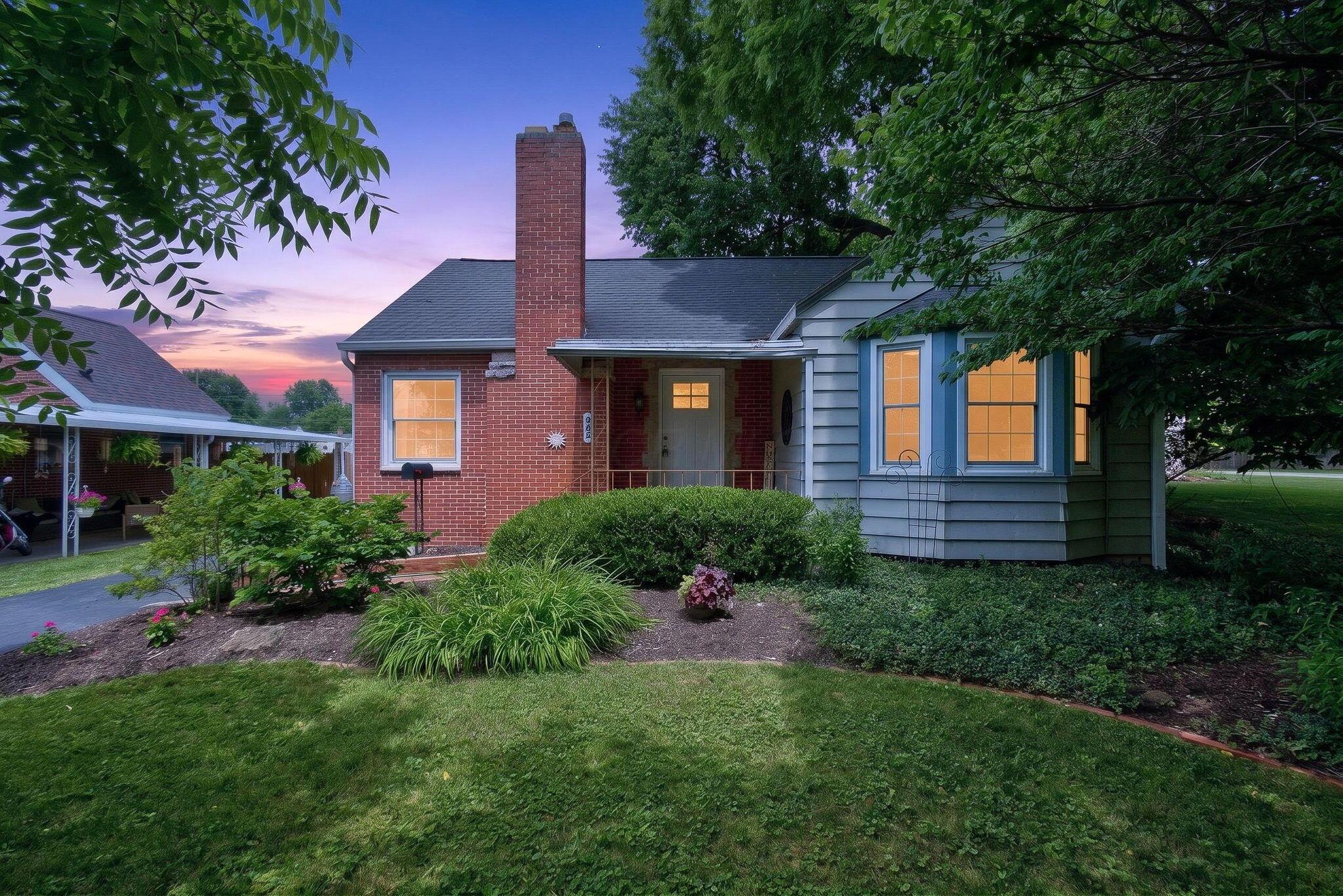 Brick and siding exterior with a prominent chimney and mature landscaping