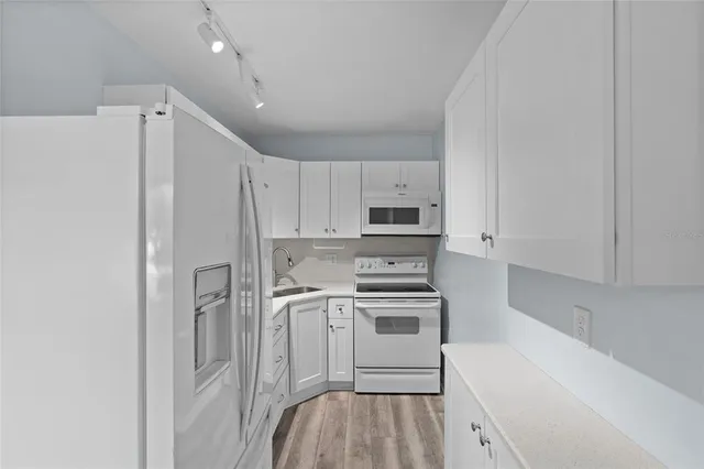 a kitchen with stainless steel appliances a refrigerator stove and white cabinets