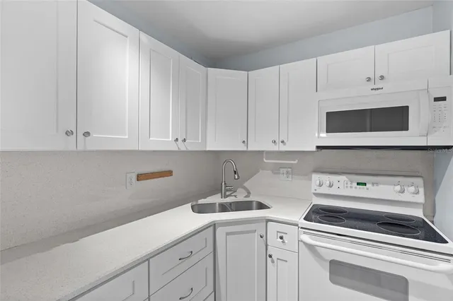 a kitchen with white cabinets and white appliances