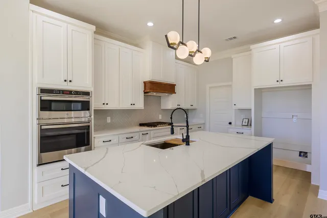 a kitchen with white cabinets and sink