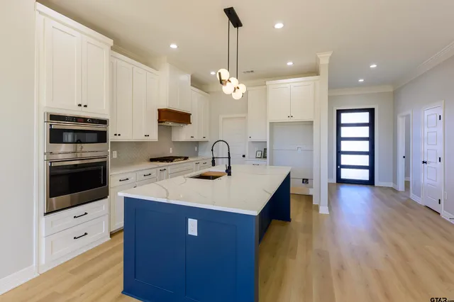 a kitchen with kitchen island a sink stainless steel appliances and wooden floor