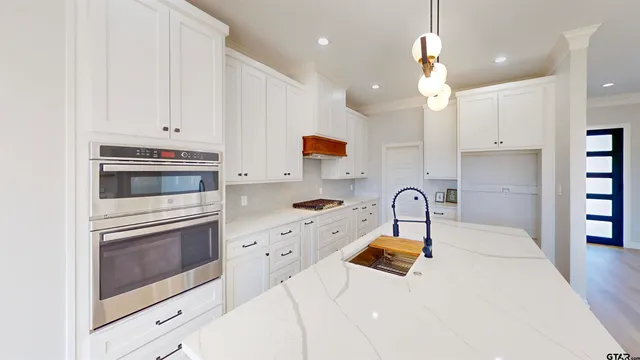 a room with stainless steel appliances kitchen island a sink a window and chairs
