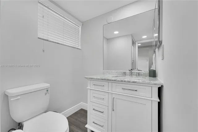 a bathroom with a granite countertop toilet sink and mirror
