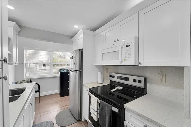 a kitchen with granite countertop a stove sink and refrigerator