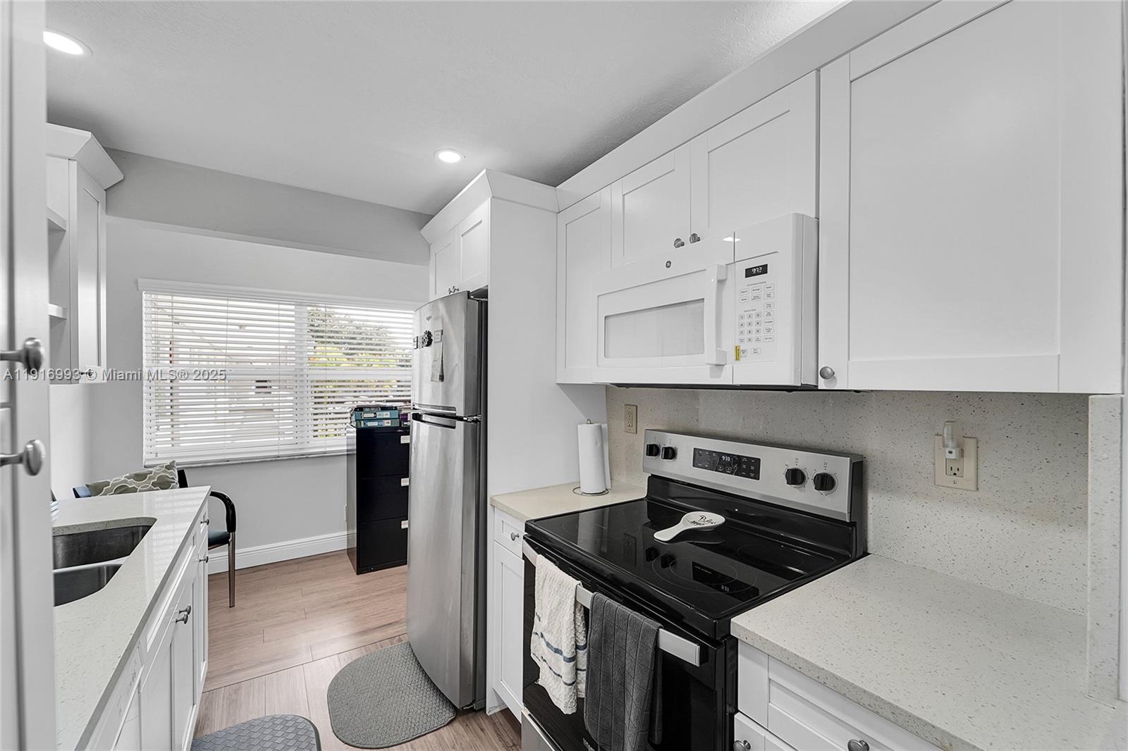 8405 Northwest 61st Street, Unit D207 Tamarac, FL 33321 - Photo 5 of 28 a kitchen with granite countertop a stove sink and refrigerator