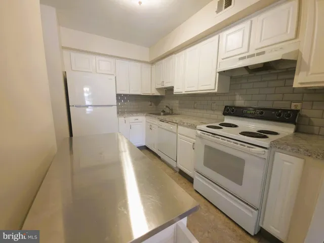a kitchen with stainless steel appliances white cabinets and a refrigerator