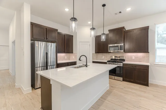 a kitchen with stainless steel appliances kitchen island a refrigerator sink and stove