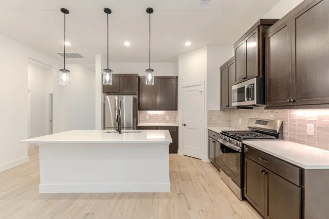 a kitchen with stainless steel appliances kitchen island granite countertop a stove a sink and a refrigerator