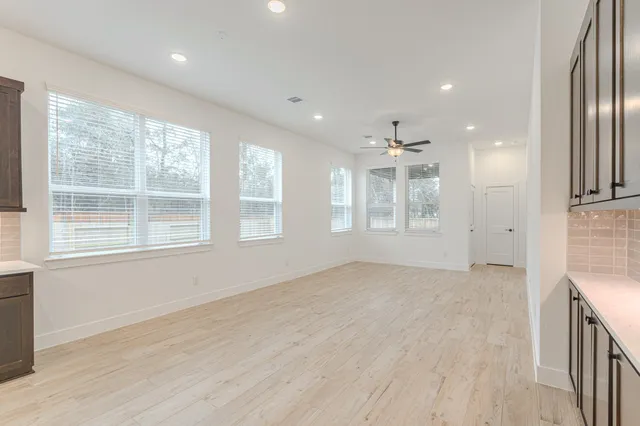 an empty room with wooden floor and windows