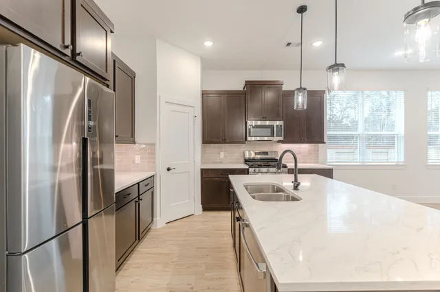 a kitchen with stainless steel appliances granite countertop a refrigerator a sink and a stove