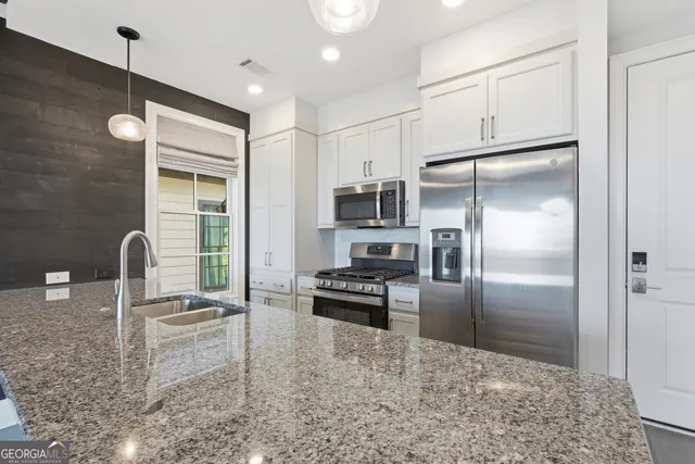 a kitchen with granite countertop a refrigerator and a sink