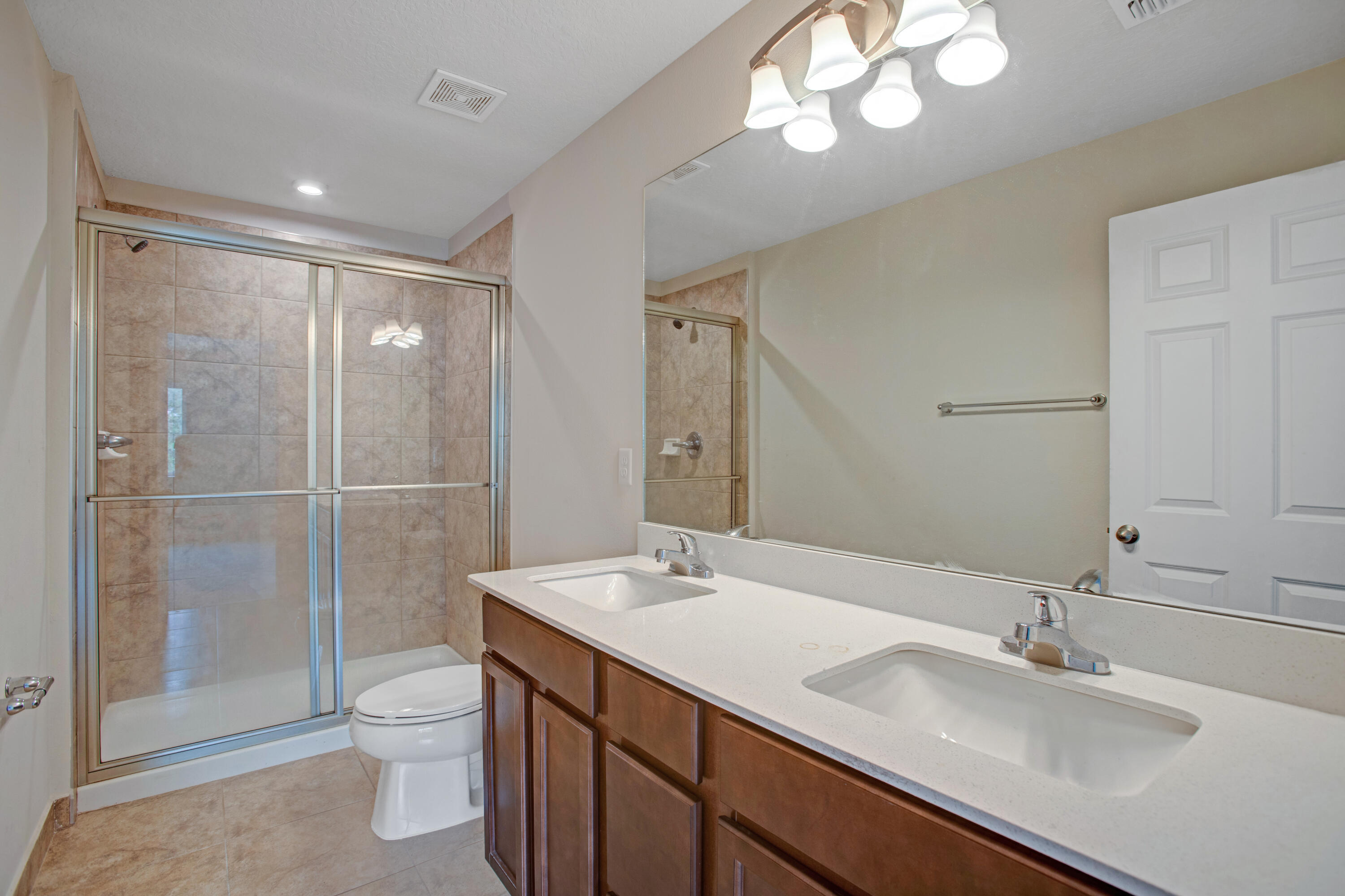 3343 Liberty Square Way, Unit 104 Fort Pierce, FL 34982 - Photo 24 of 34 a bathroom with a sink a toilet and a large mirror