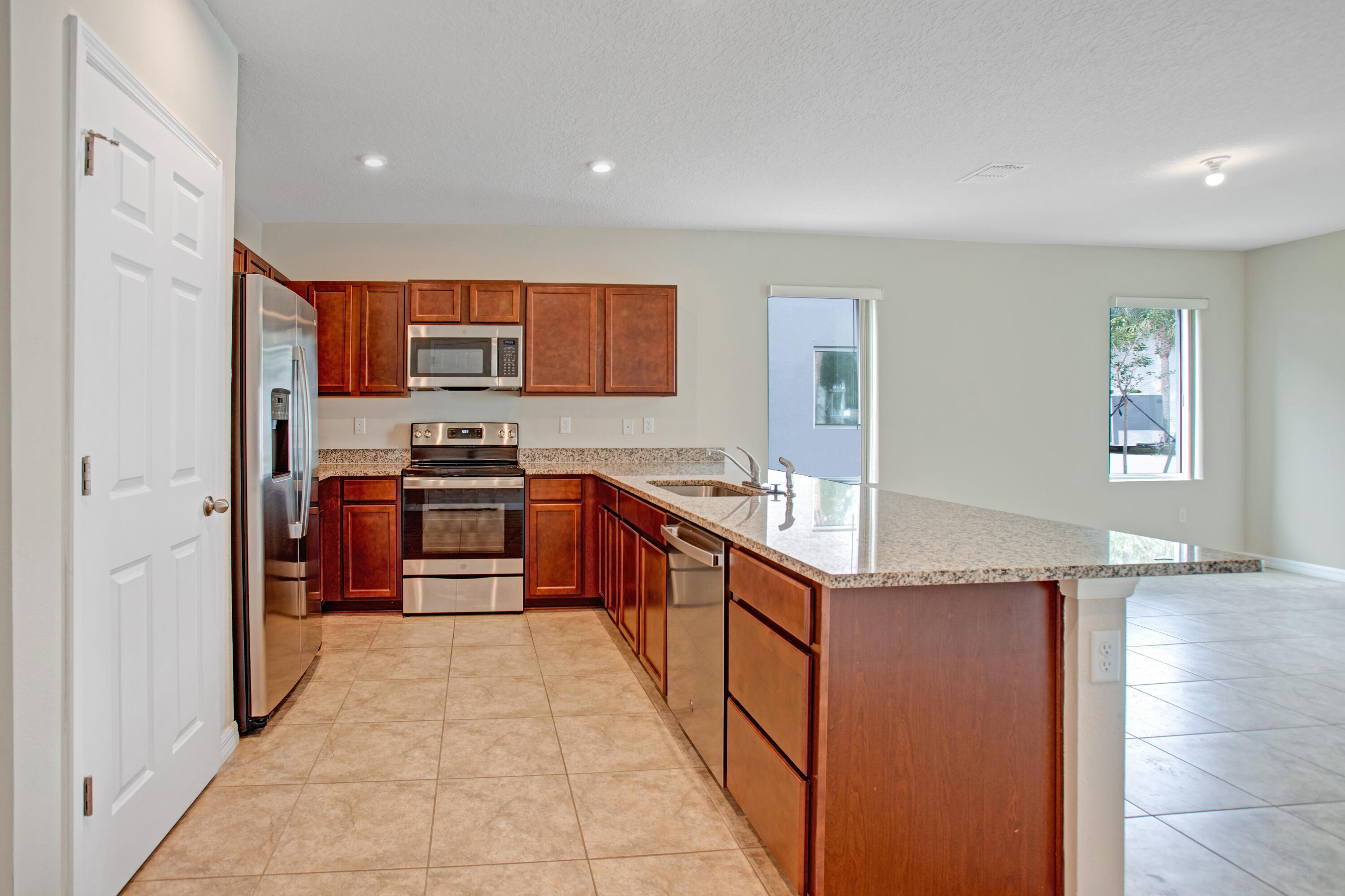 3343 Liberty Square Way, Unit 104 Fort Pierce, FL 34982 - Photo 7 of 34 a kitchen with stainless steel appliances granite countertop a stove a sink and a refrigerator