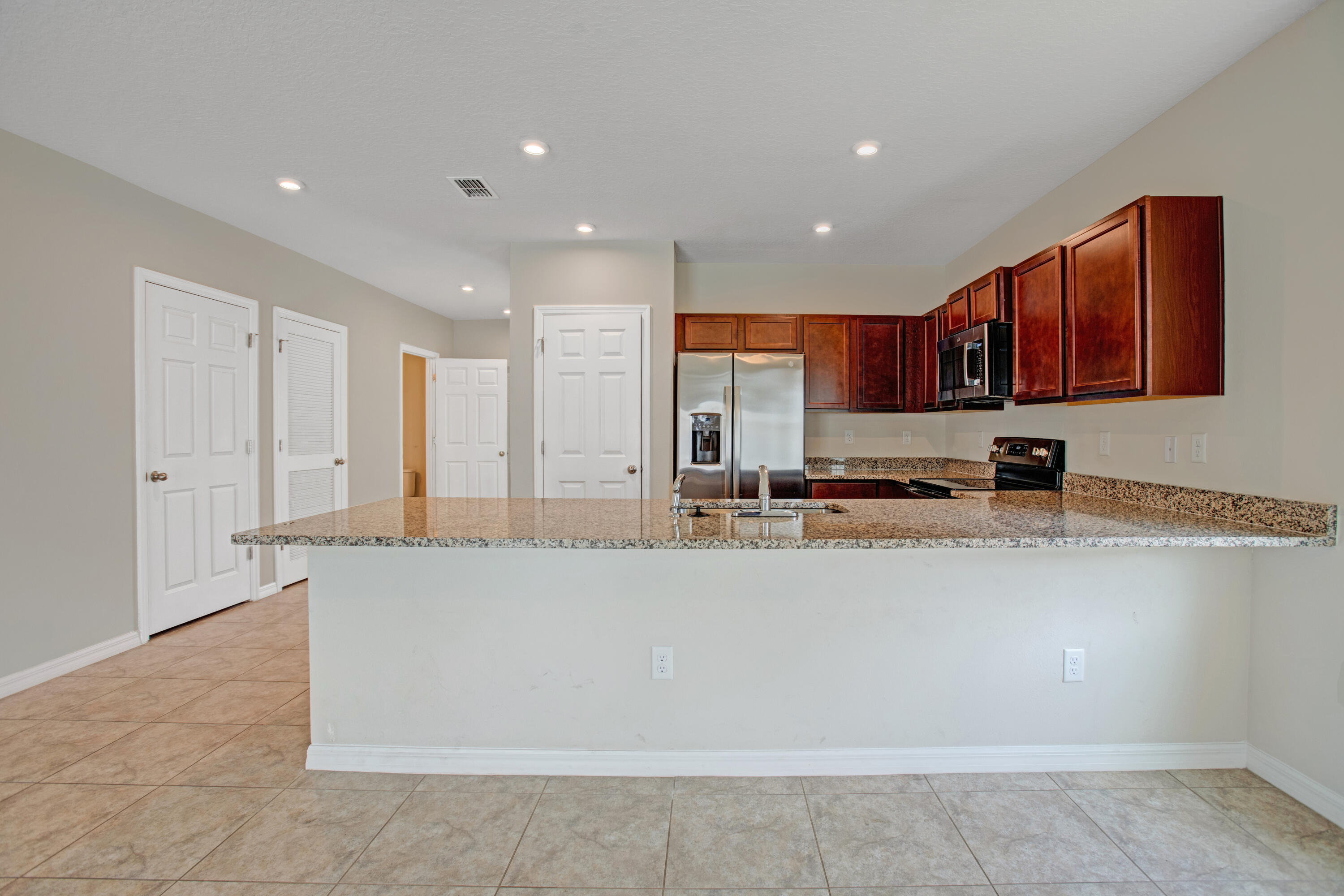 3343 Liberty Square Way, Unit 104 Fort Pierce, FL 34982 - Photo 8 of 34 a large kitchen with stainless steel appliances a large counter top a stove a microwave a sink and a refrigerator