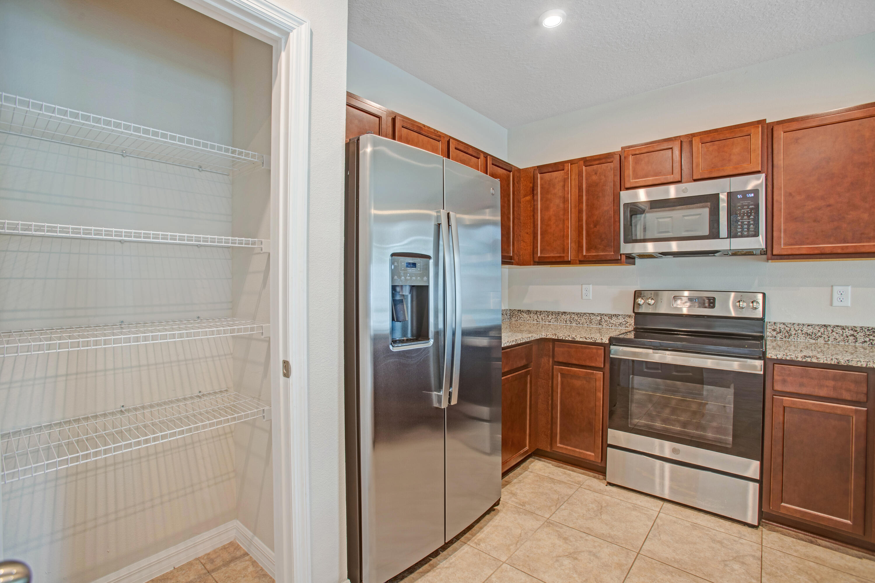 3343 Liberty Square Way, Unit 104 Fort Pierce, FL 34982 - Photo 10 of 34 a kitchen with stainless steel appliances granite countertop a refrigerator and a stove top oven