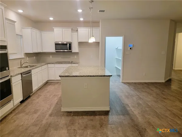 a large kitchen with stainless steel appliances granite countertop a stove a sink and a refrigerator