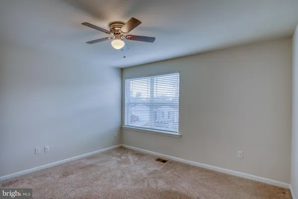 an empty room with a window and a fan