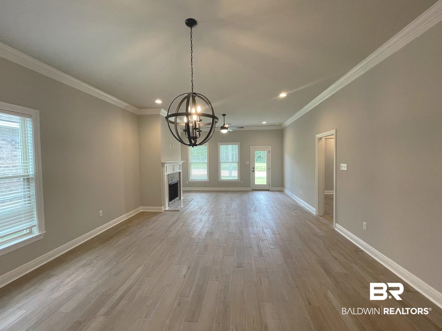 1412 Fenton Circle Foley, AL 36535 - Photo 4 of 15 Unfurnished living room featuring light hardwood / wood-style floors, ceiling fan with notable chandelier, and crown molding
