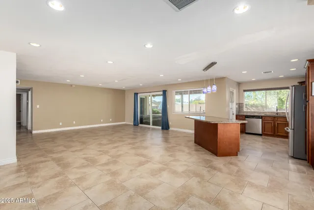 a view of kitchen island a refrigerator wooden floor and a chandelier