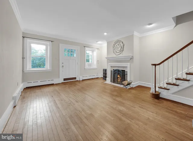 an empty room with fireplace wooden floor and windows