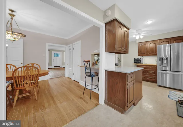 a kitchen with stainless steel appliances granite countertop a refrigerator a stove a sink dishwasher a dining table and chairs with wooden floor