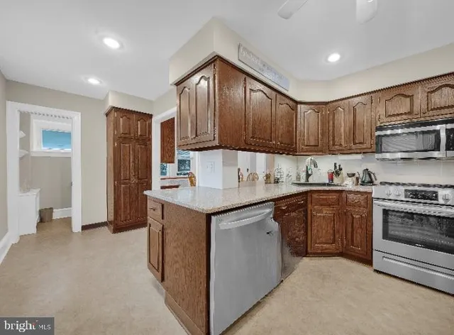 a kitchen with kitchen island granite countertop wooden cabinets a sink and a stove
