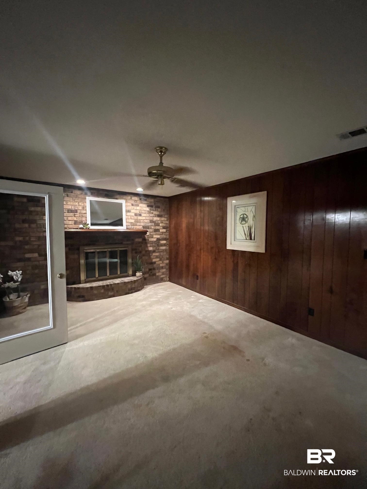2240 Perdido Circle Lillian, AL 36549 - Photo 9 of 42 Unfurnished living room featuring carpet floors, wood walls, ceiling fan, and a brick fireplace