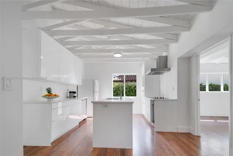 a living room with wooden floors and kitchen view