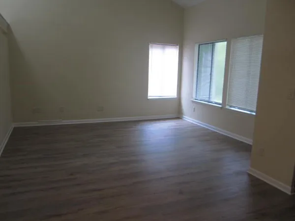 an empty room with wooden floor and fan