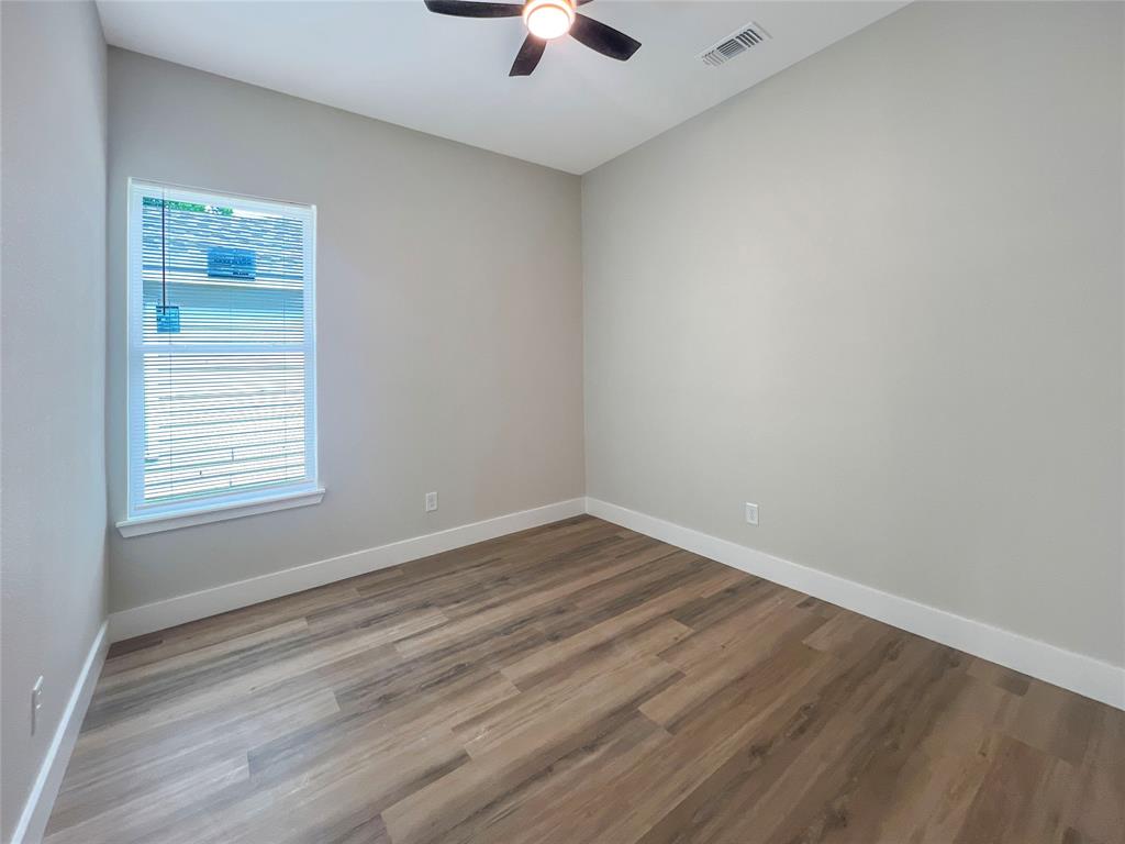 4006 Coolidge Street Dallas, TX 75215 - Photo 12 of 27 an empty room with wooden floor chandelier fan and windows