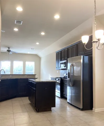 a kitchen with kitchen island a counter top space a sink and a refrigerator