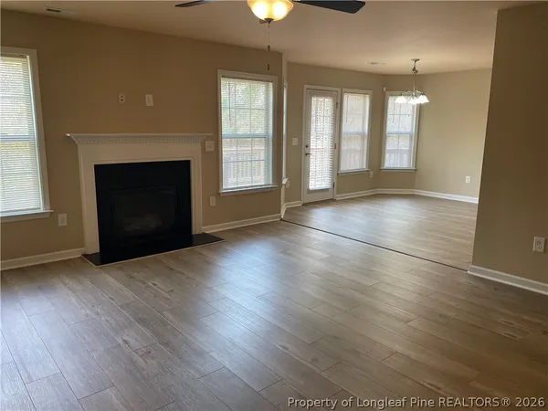 an empty room with wooden floor fireplace and windows
