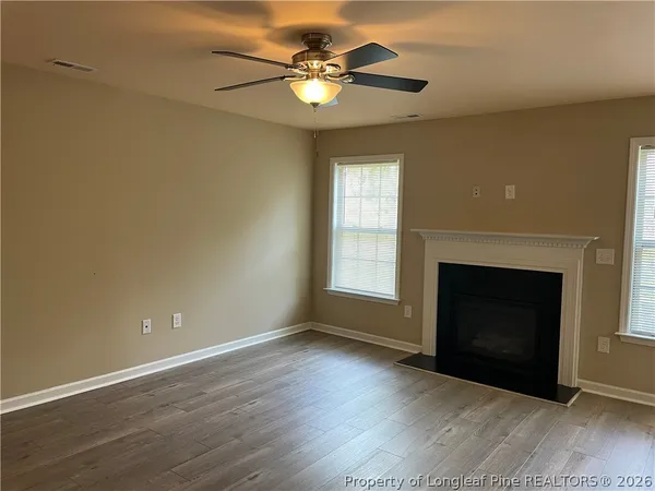 an empty room with windows and fireplace