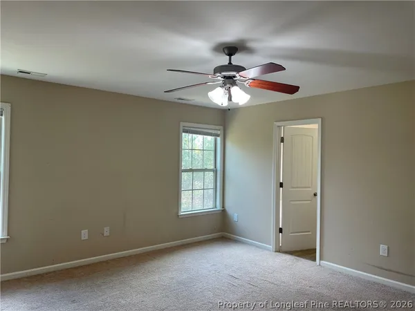 an empty room with chandelier fan and windows