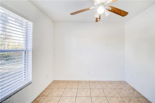 an empty room with a window and a ceiling fan