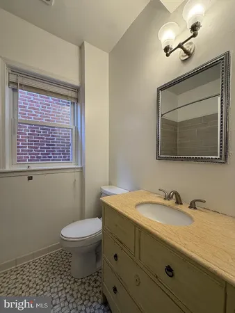 a bathroom with a granite countertop toilet a sink a mirror and a window