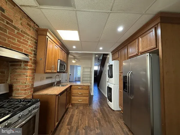 a kitchen with stainless steel appliances granite countertop a refrigerator a sink dishwasher a stove and white countertops with wooden floor