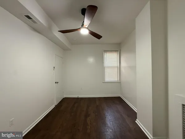 an empty room with wooden floor ceiling fan and windows